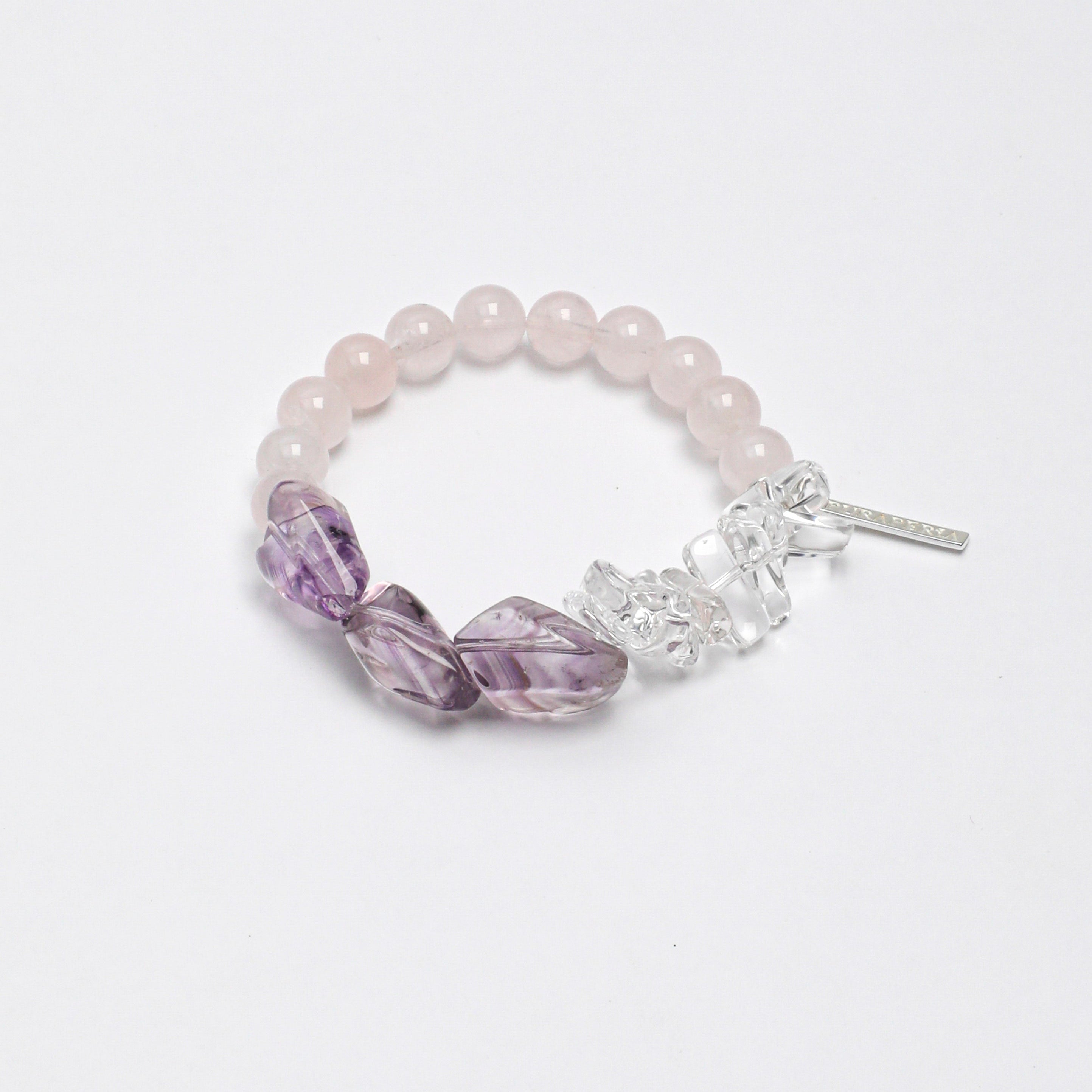 Handcrafted stretch bracelet featuring natural Rose Quartz beads, carved Amethyst leaf gemstones, Clear Quartz crystal chips, and a silver tassel charm on a durable elastic band.