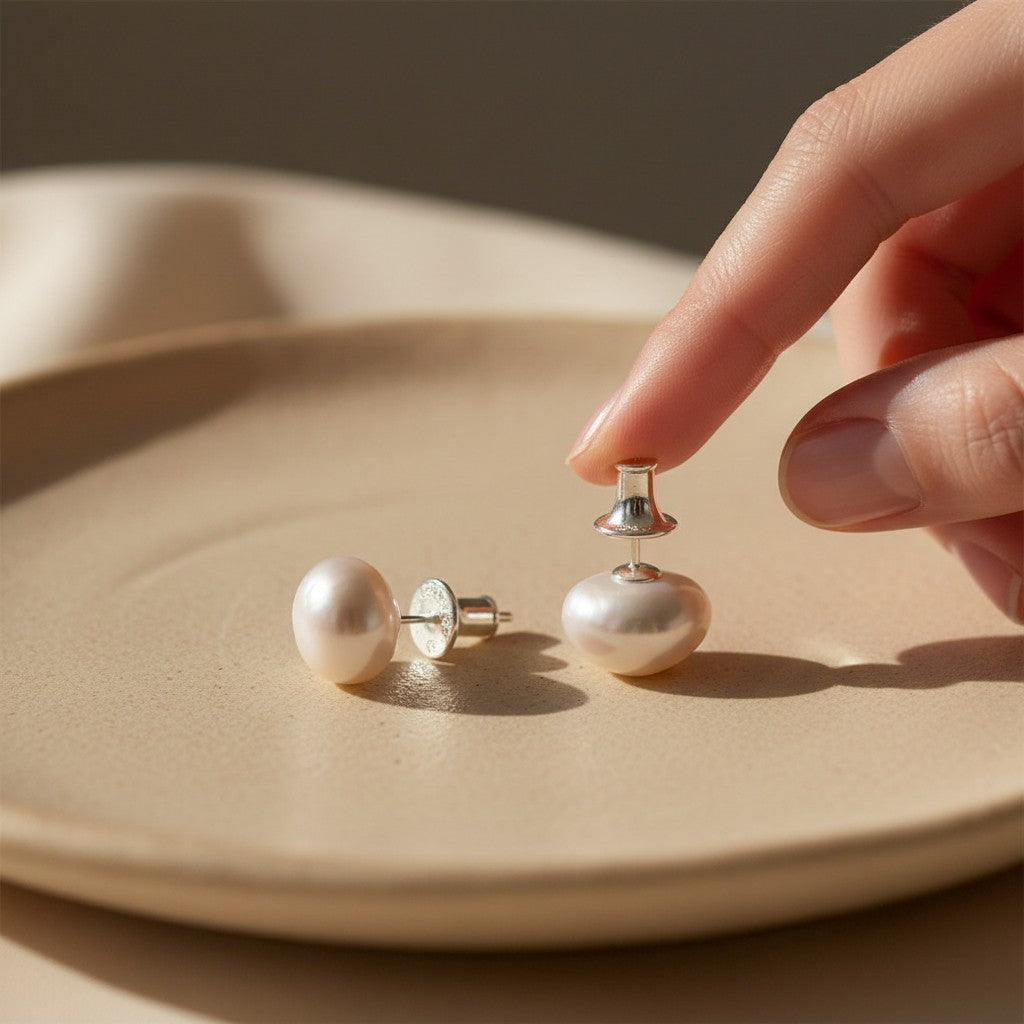 Elegant pearl stud earrings with 925 sterling silver posts displayed on a warm neutral jewelry tray