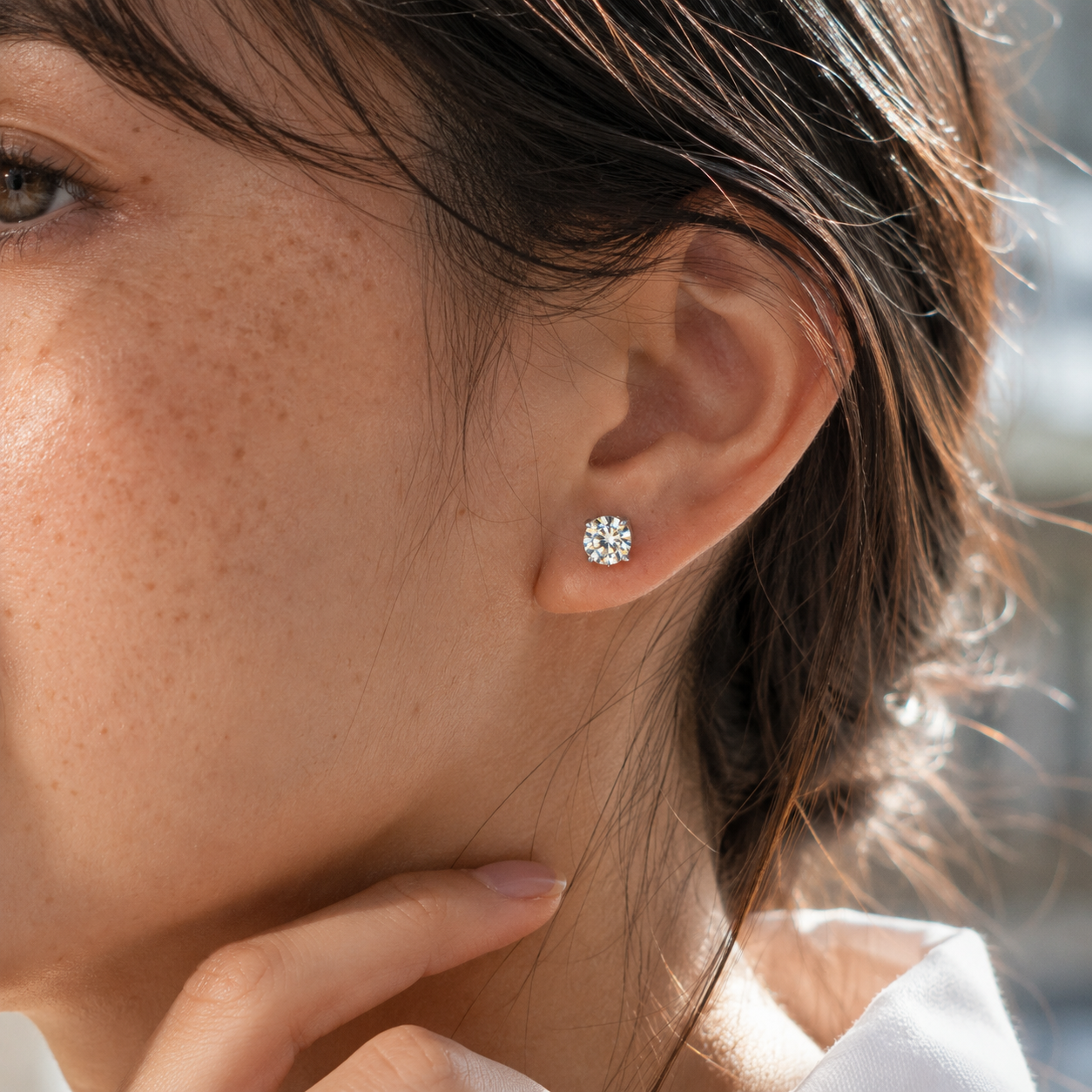 Close-up of the left ear wearing 925 sterling silver round moissanite stud earrings