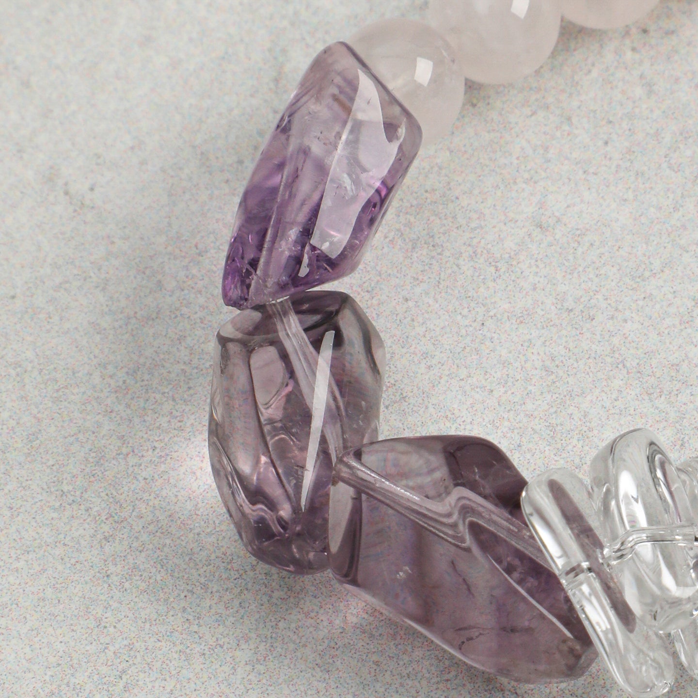 Close-up of faceted amethyst gemstone accents on handmade rose quartz bracelet