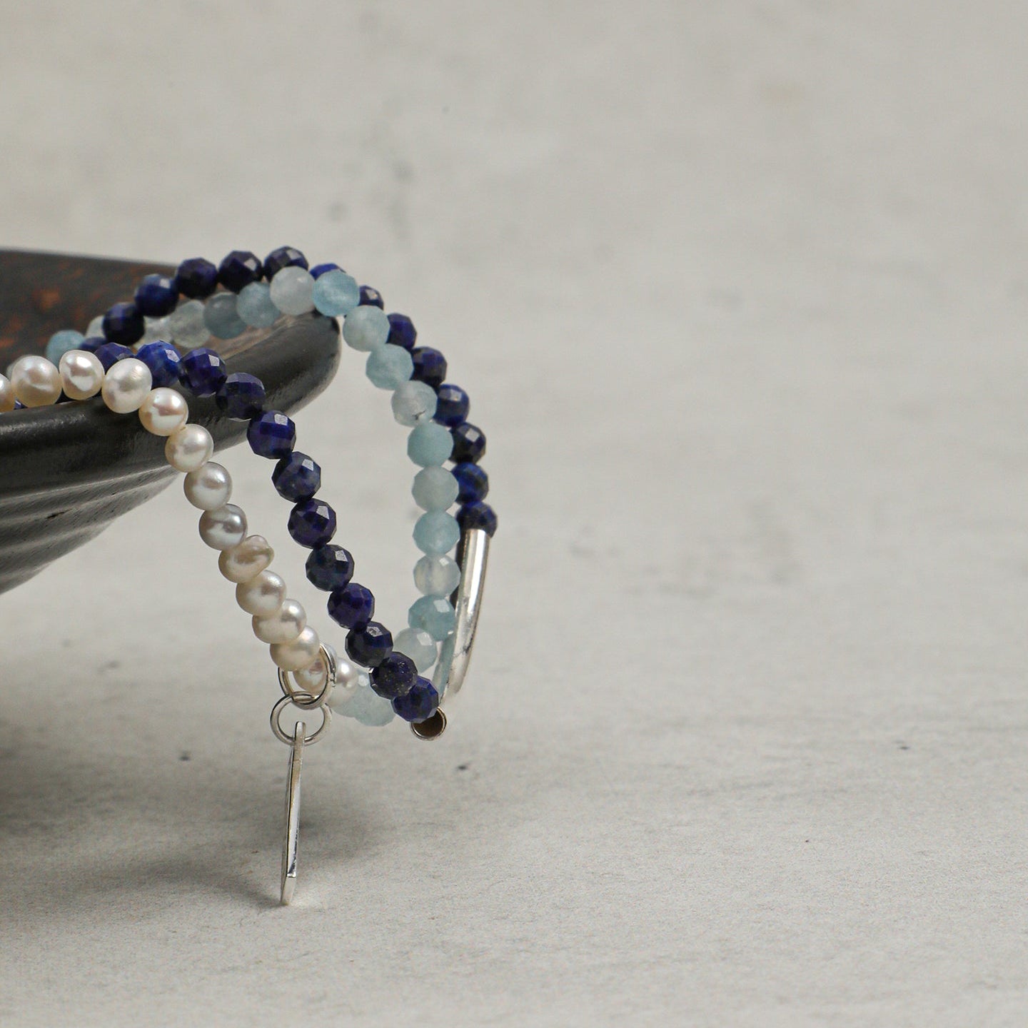 Close-up of aquamarine, lapis lazuli and freshwater pearl layered bracelet with silver accents