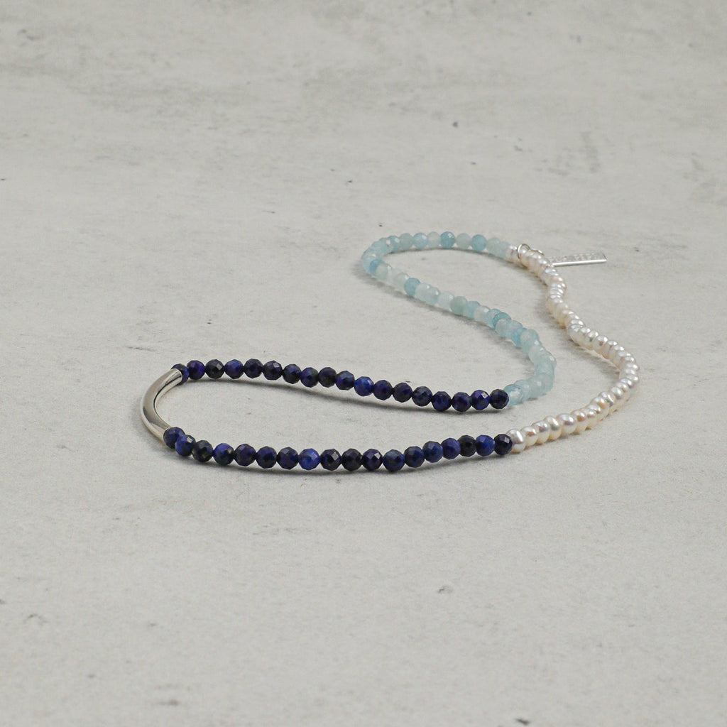 Full-length view of aquamarine, lapis lazuli and freshwater pearl layered bracelet with silver accent