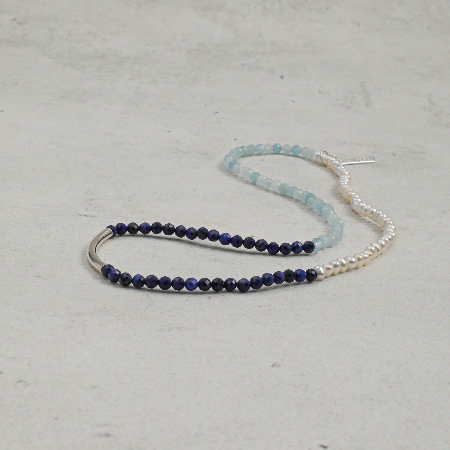 Full-length view of aquamarine, lapis lazuli and freshwater pearl layered bracelet with silver accent