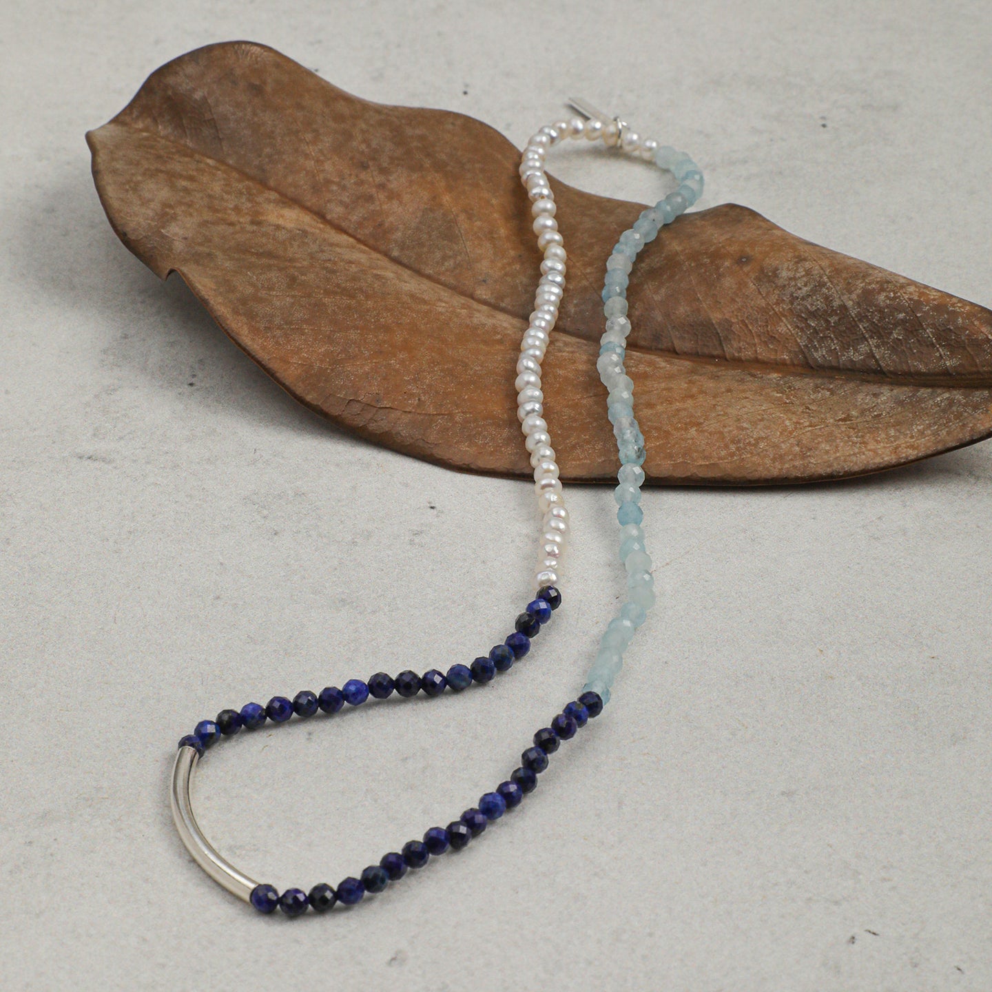 Aquamarine, lapis lazuli and freshwater pearl layered bracelet styled with a natural dried leaf
