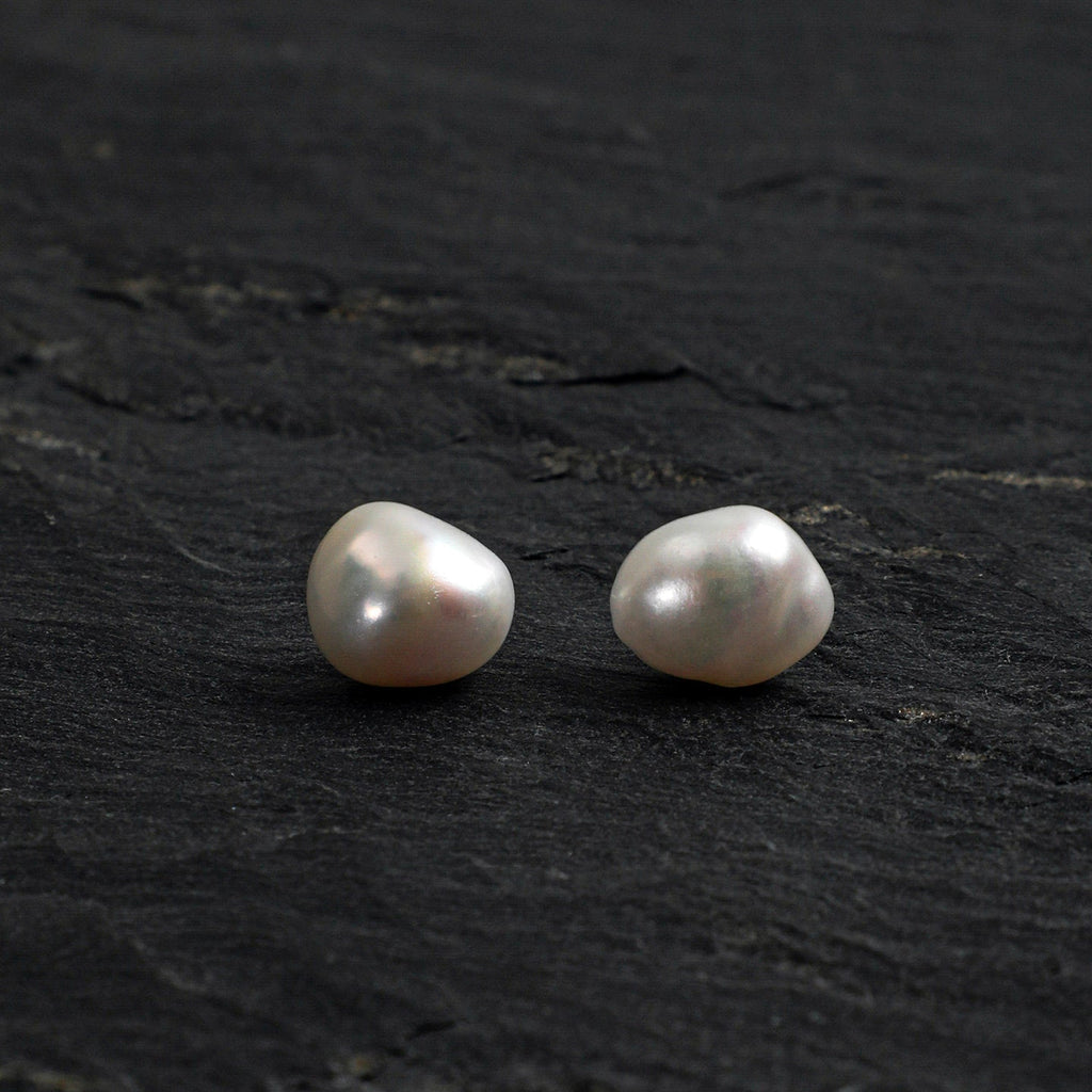 Baroque pearl stud earrings front view on dark stone background