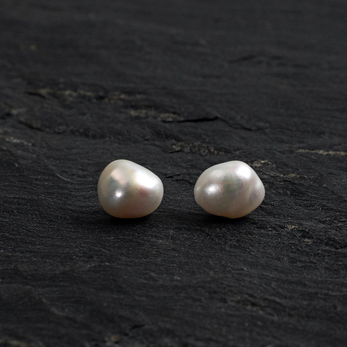 Baroque pearl stud earrings front view on dark stone background