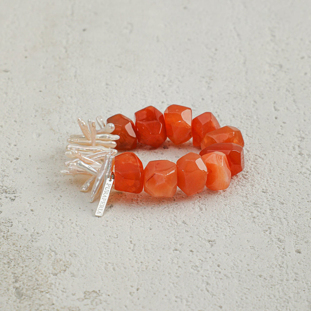 Angled view of handcrafted carnelian and elongated freshwater pearl statement bracelet