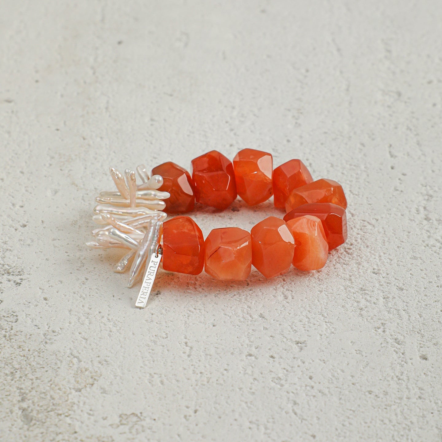 Angled view of handcrafted carnelian and elongated freshwater pearl statement bracelet