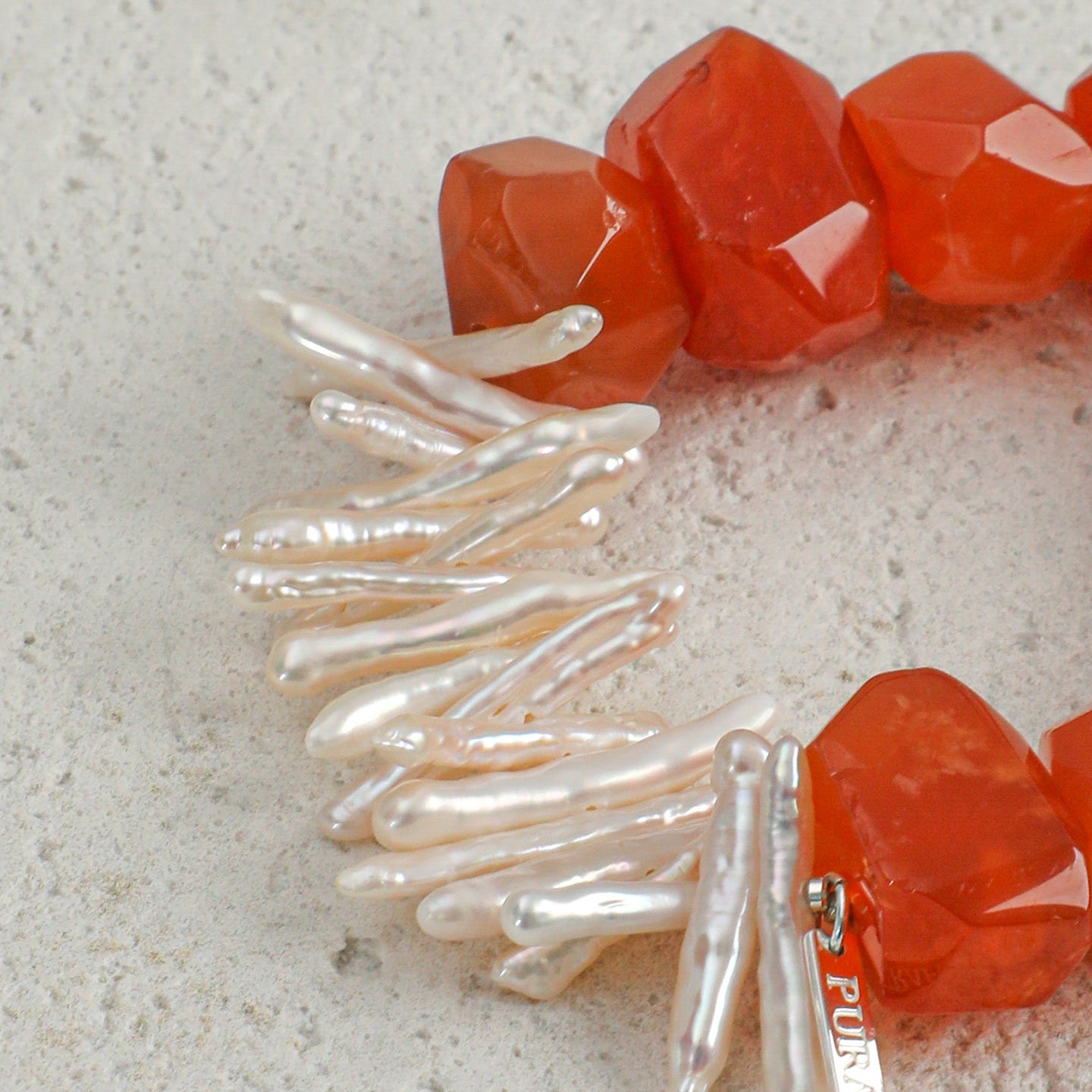 Close-up of elongated freshwater pearls and faceted carnelian gemstones on statement bracelet