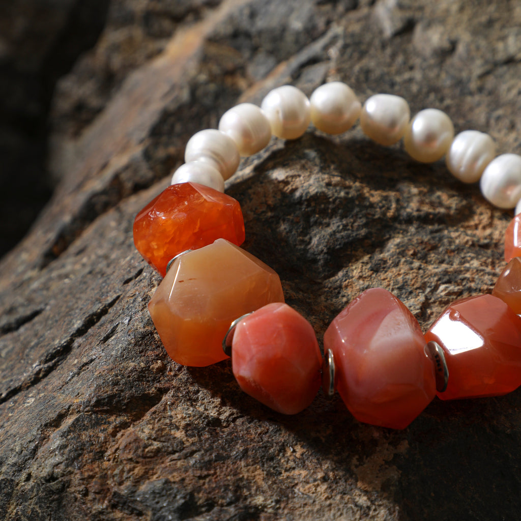 Close-up of faceted carnelian gemstones and freshwater pearls on statement bracelet