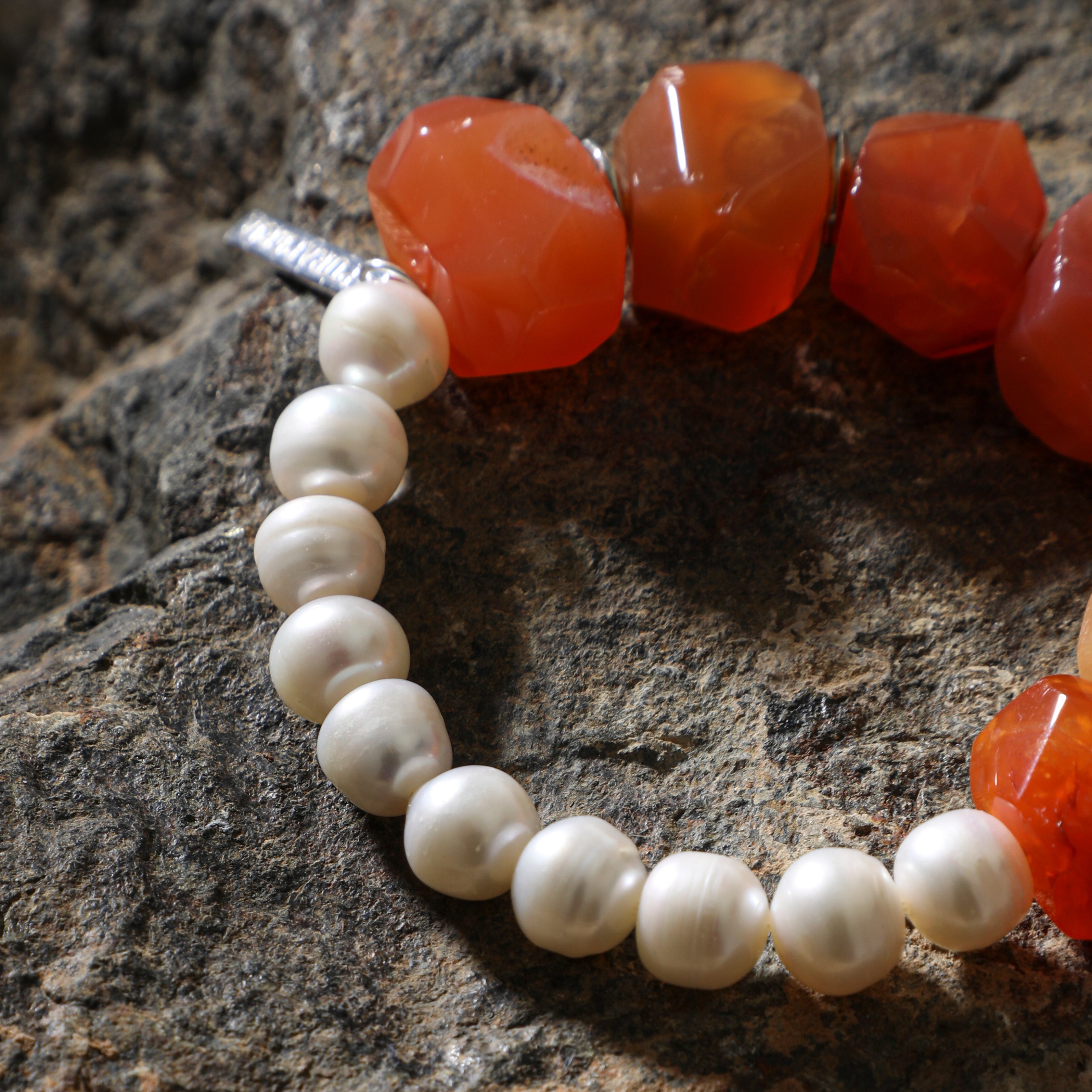 Close-up of freshwater pearls and faceted carnelian gemstones on statement bracelet