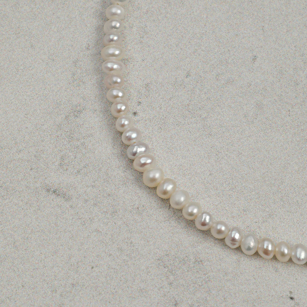 Close-up of natural freshwater pearls on layered gemstone bracelet