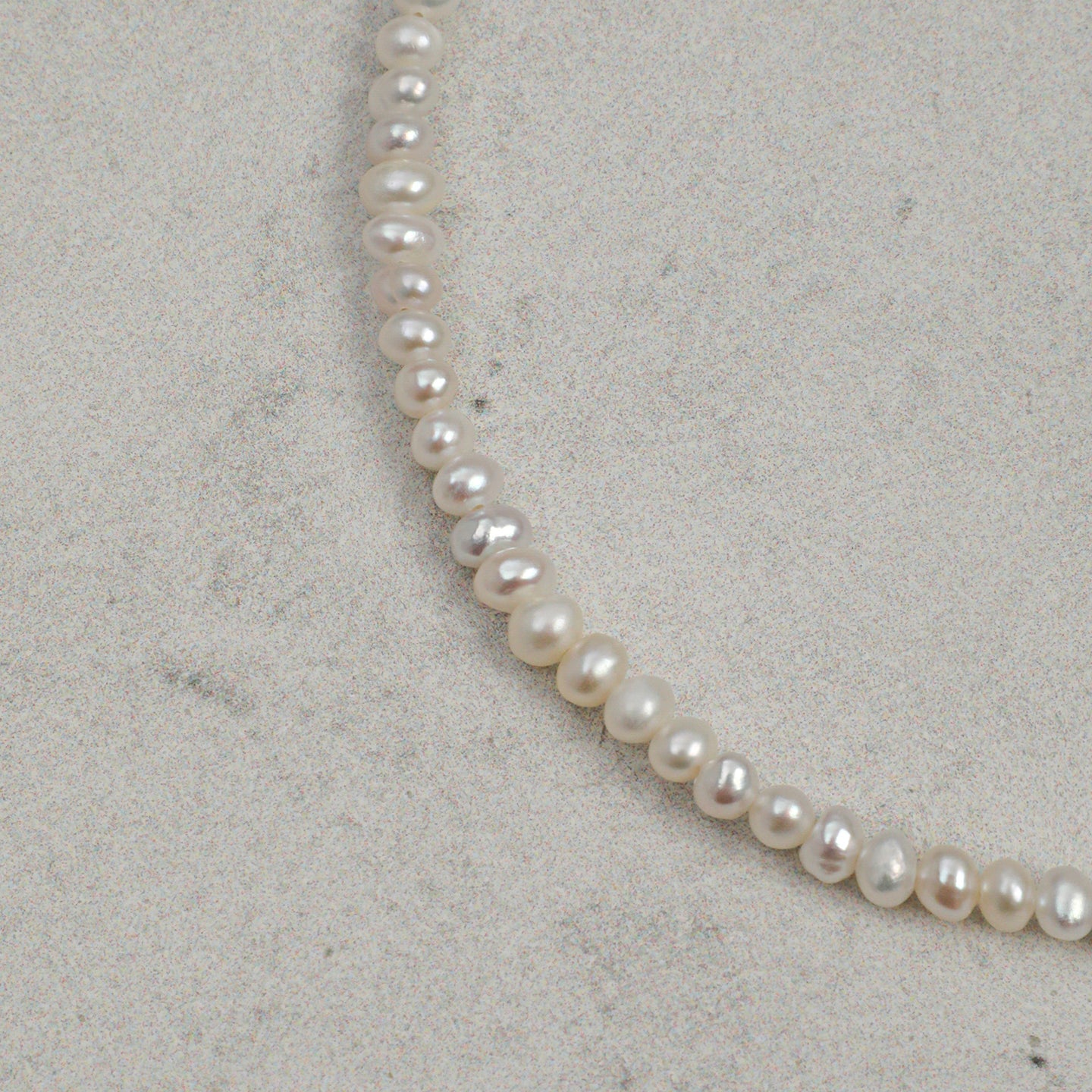 Close-up of natural freshwater pearls on layered gemstone bracelet