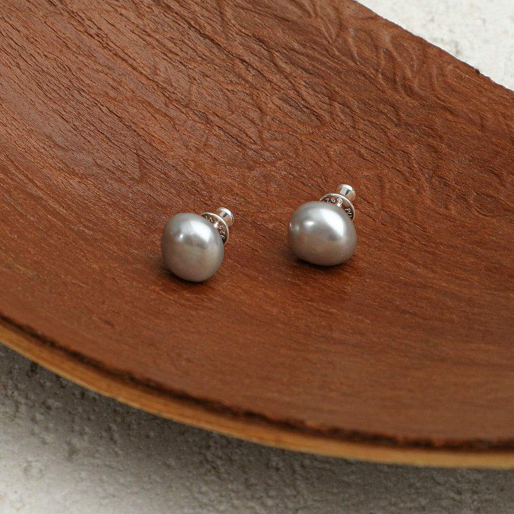 Grey baroque freshwater pearl stud earrings styled on a natural wood surface