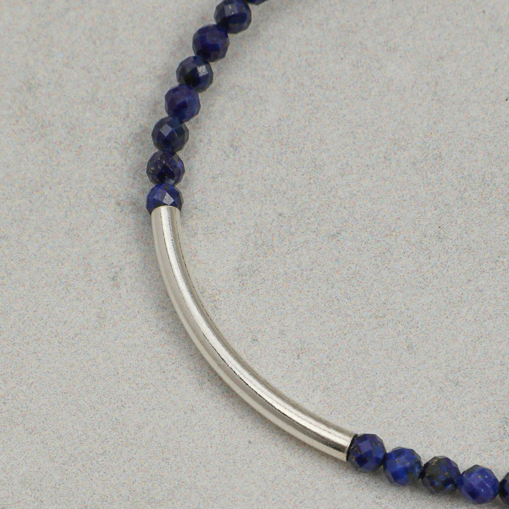 Close-up of faceted lapis lazuli beads with curved silver bar accent