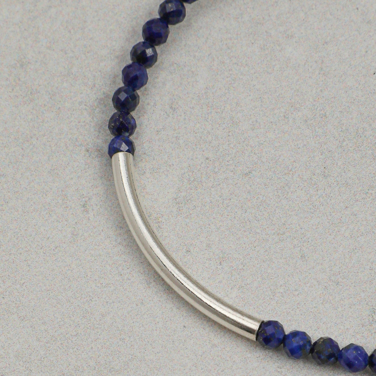Close-up of faceted lapis lazuli beads with curved silver bar accent