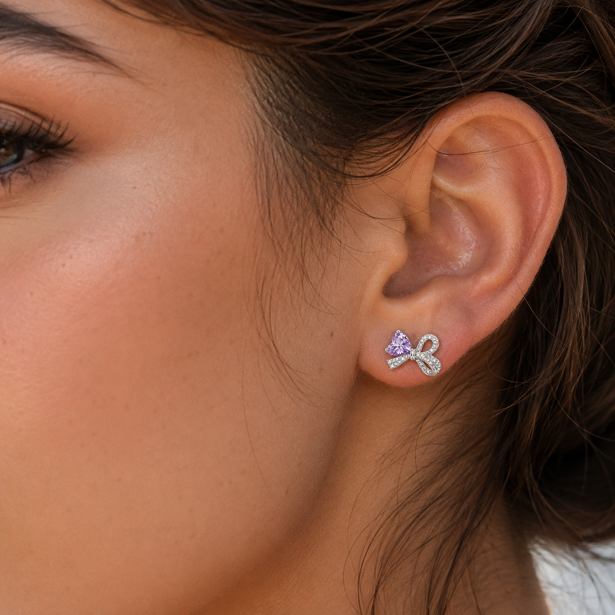 Close-up of a model wearing a Lavender Ice-Cut CZ Bow stud earring on the left ear