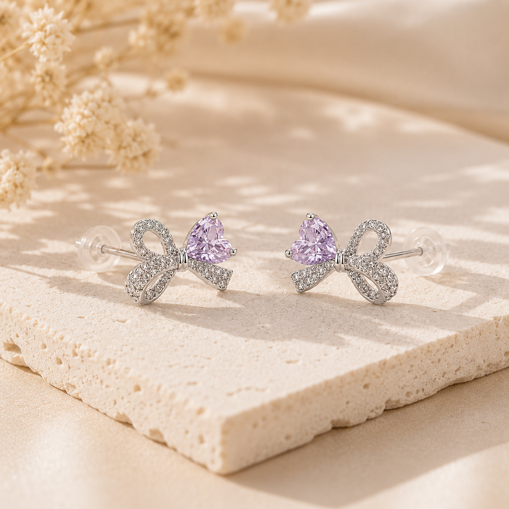 Lavender Ice-Cut CZ Bow stud earrings in rhodium-plated 925 sterling silver displayed on a warm neutral stone surface