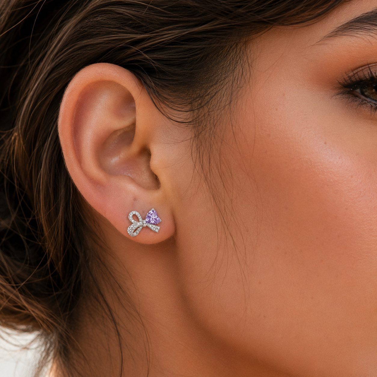 Close-up of a model wearing a Lavender Ice-Cut CZ Bow stud earring on the right ear