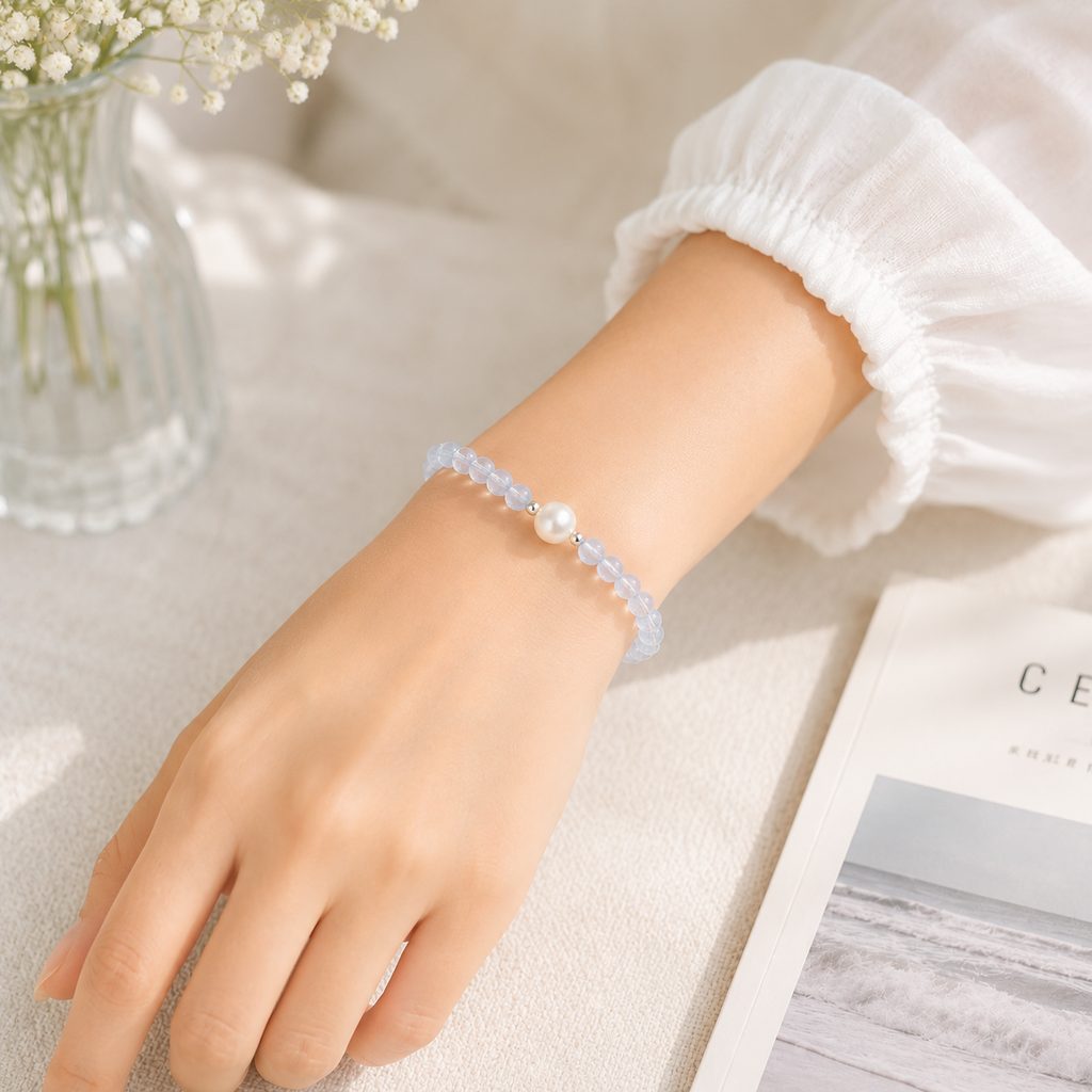 Close-up of a woman wearing a handmade natural aquamarine bracelet featuring 4mm aquamarine beads, an 8mm genuine freshwater pearl and silver-tone spacer beads in soft natural light.