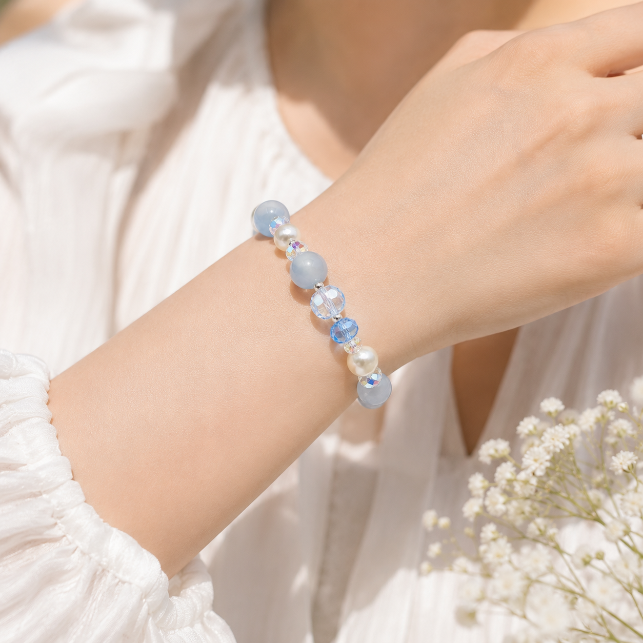Close-up of a woman wearing a handmade bracelet featuring 10mm natural aquamarine beads, 8mm genuine freshwater pearls, 8mm blue faceted crystal beads, 6mm aurora crystal accent beads and silver-tone spacer beads.