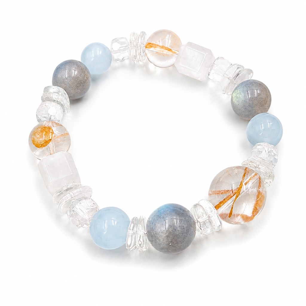 Handmade bracelet featuring 10mm natural grey moonstone, aquamarine and golden rutilated quartz beads, 10mm natural white quartz cube beads, faceted clear quartz accent beads and clear quartz cloud spacer beads on a white background.