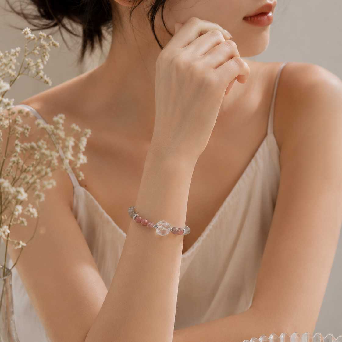 Close-up of a woman wearing a handmade natural grey moonstone bracelet featuring 4mm grey moonstone beads, a freeform clear quartz focal bead, strawberry quartz accent beads and silver-tone spacer beads.
