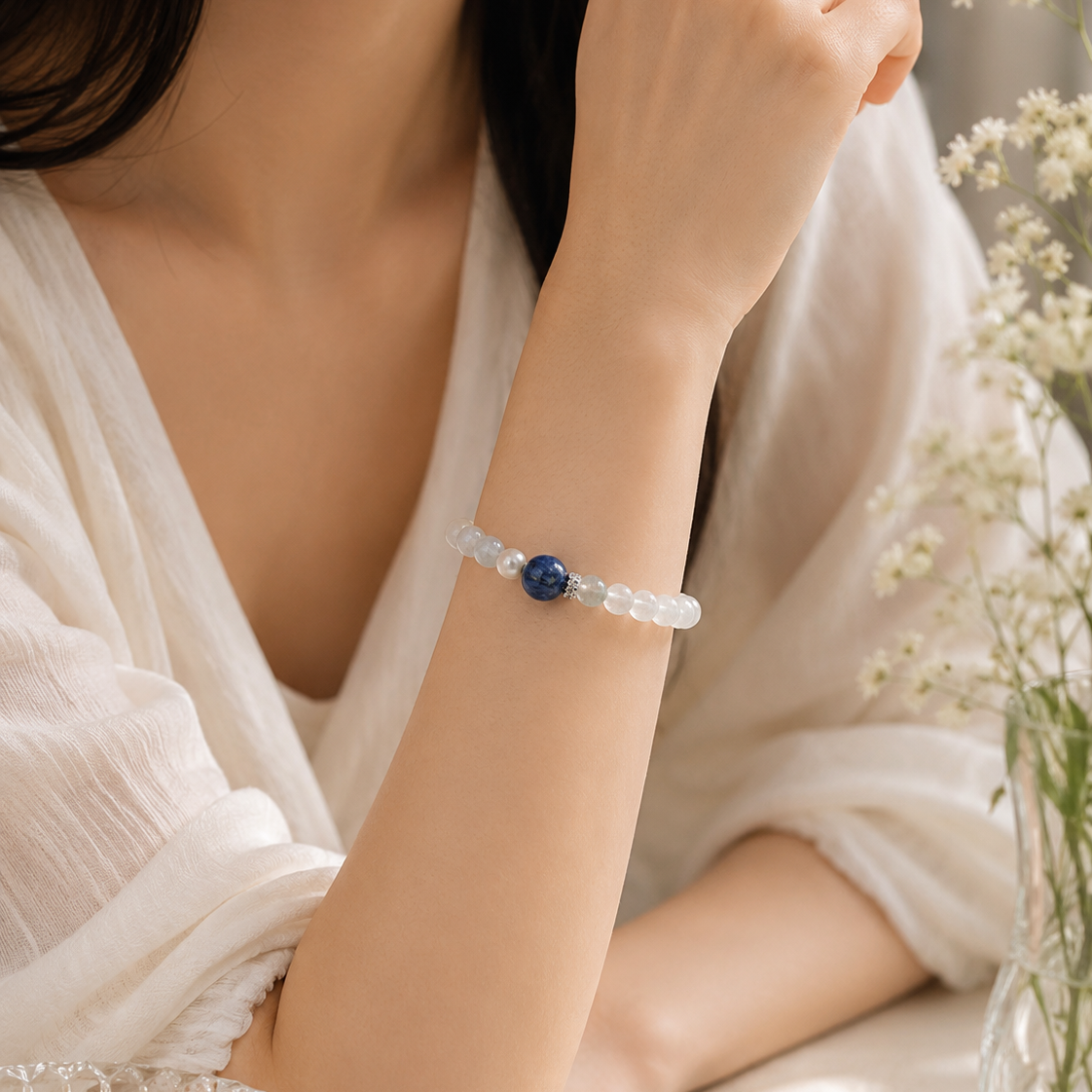 Close-up of a woman wearing a handmade natural moonstone bracelet featuring 5mm moonstone beads, a 10mm blue kyanite focal bead and 7mm freshwater pearls.