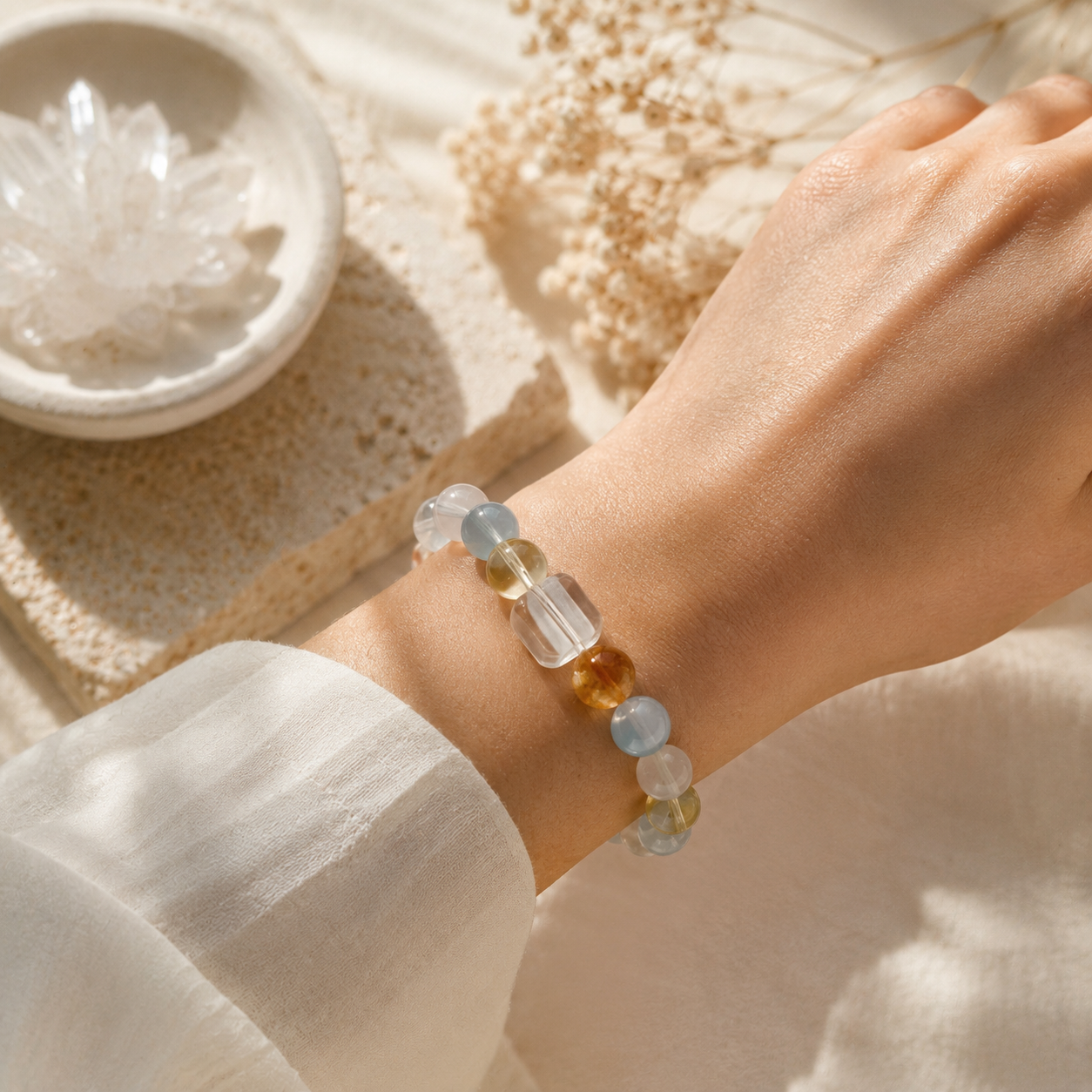 Close-up of a woman wearing a handmade bracelet featuring 10mm natural yellow flower quartz, aquamarine, white quartz, citrine and clear quartz beads with a 10mm faceted clear quartz cube bead.
