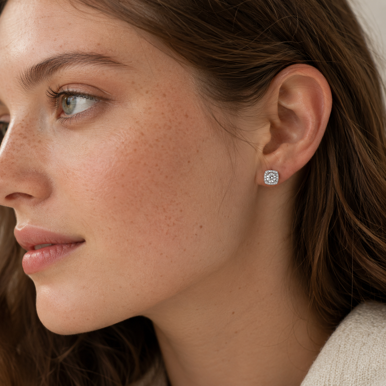 Platinum plated 925 sterling silver square halo moissanite stud earrings worn on left ear