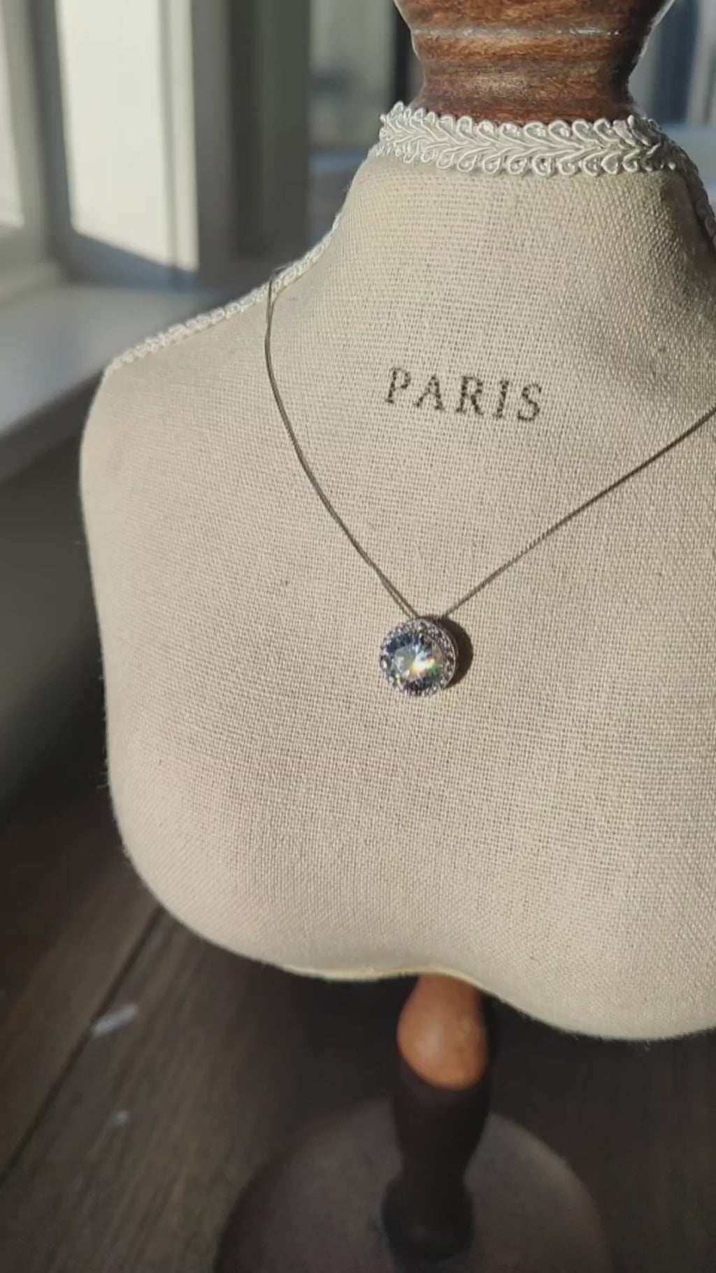 925 sterling silver round CZ pendant necklace displayed on a linen jewellery bust in natural sunlight.