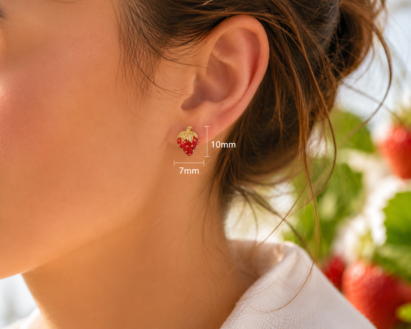 Red strawberry gold-tone stud earring worn on ear showing 10 mm height and 7 mm width
