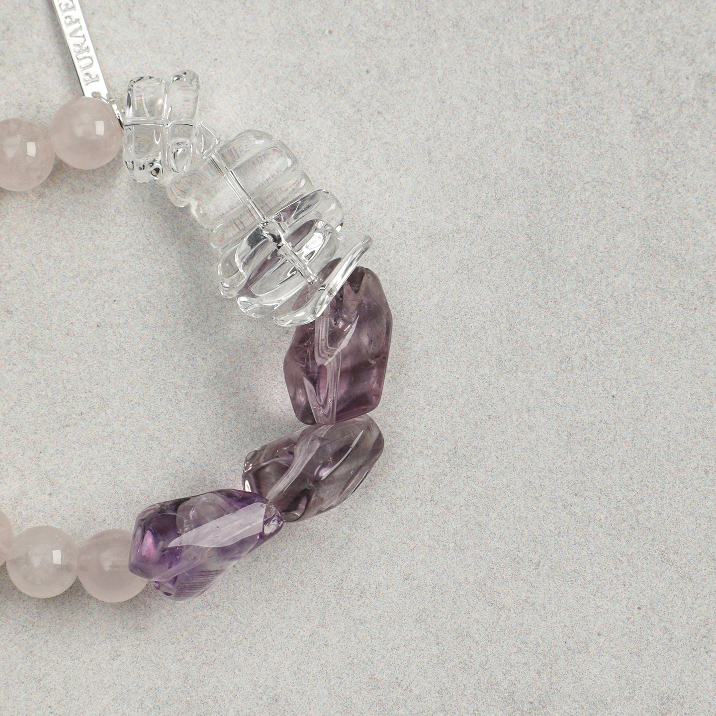 Close-up of rose quartz bracelet with carved amethyst and clear quartz gemstone accents