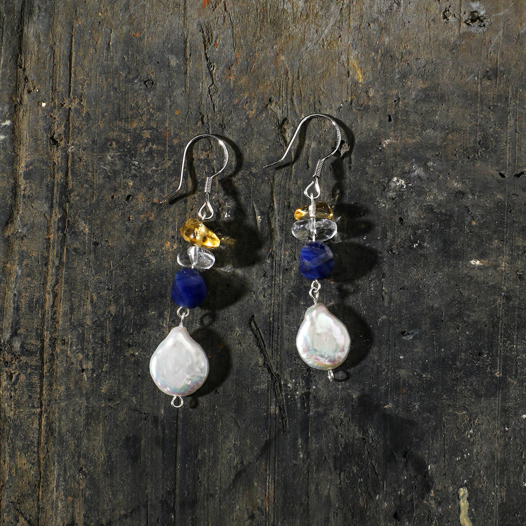 Sodalite, citrine and freshwater pearl drop earrings styled on a dark natural surface
