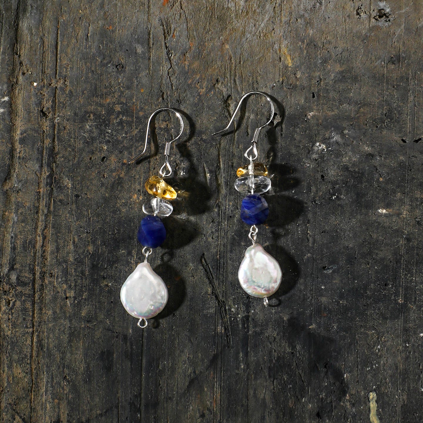 Sodalite, citrine and freshwater pearl drop earrings styled on a dark natural surface