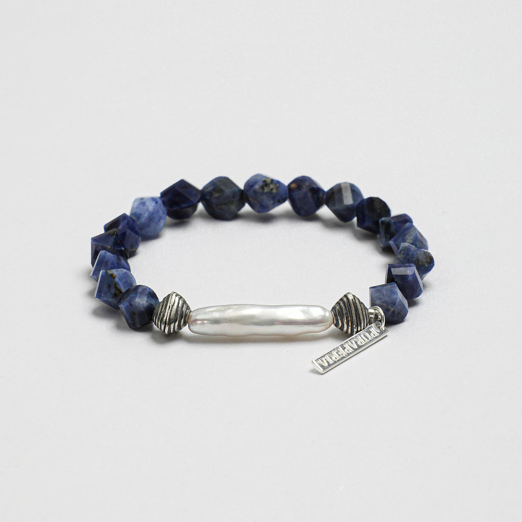 Angled view of handcrafted sodalite and freshwater pearl statement bracelet with textured silver-tone accents