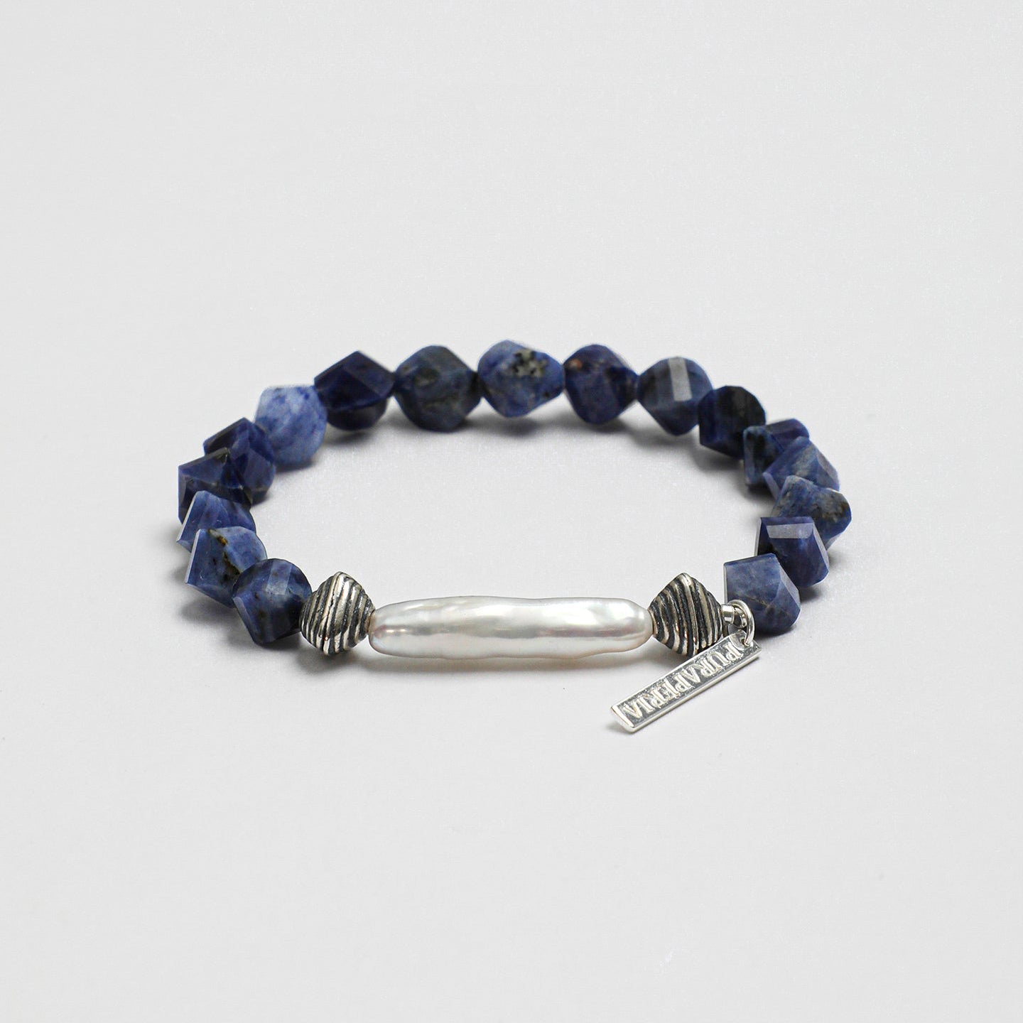 Angled view of handcrafted sodalite and freshwater pearl statement bracelet with textured silver-tone accents