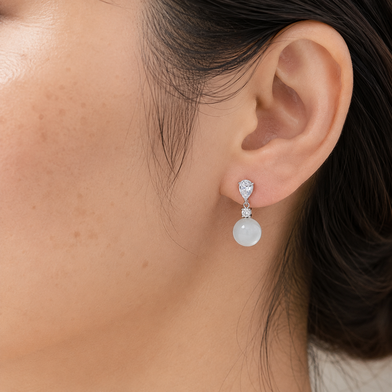 Close-up of a 40-year-old Asian woman wearing White Chalcedony drop earrings in the left ear