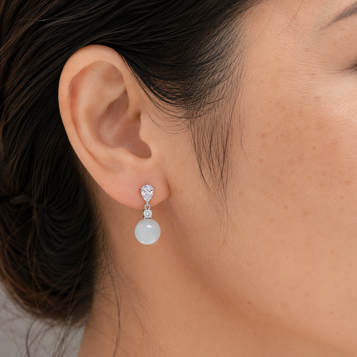 Close-up of a 40-year-old Asian woman wearing White Chalcedony drop earrings in the right ear
